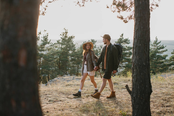 Хлопець і дівчина йдуть разом тримаючи руки під час походу в гори.  - Фото, зображення