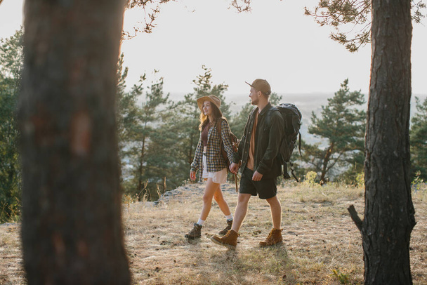 Ένας άντρας και ένα κορίτσι περπατούν μαζί κρατώντας τα χέρια κατά τη διάρκεια μιας πεζοπορίας στα βουνά..  - Φωτογραφία, εικόνα