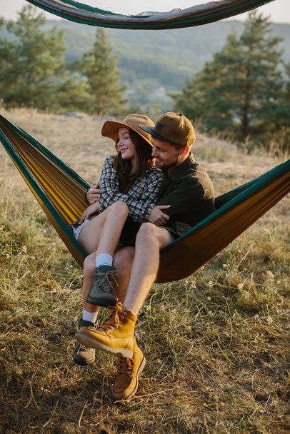 Een paar verliefd zijn knuffelen terwijl liggend in een hangmat in de natuur. - Foto, afbeelding