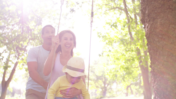 Familia con niña balanceándose en el parque
 - Metraje, vídeo