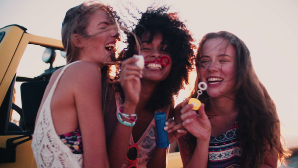 Chicas amigas divirtiéndose soplando burbujas
 - Metraje, vídeo