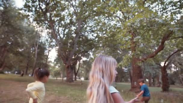 Kids running and chasing bubbles in park - Imágenes, Vídeo