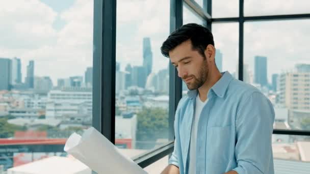 Professional engineer smiling while looking at skyscraper view. Skilled architect in casual outfit looking, planning plan project while standing near panorama window with city scape. Tracery - Footage, Video