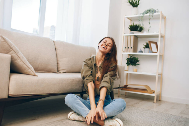 Confort à la maison confortable : une femme heureuse se relaxant sur un canapé moderne dans son salon paisible. - Photo, image