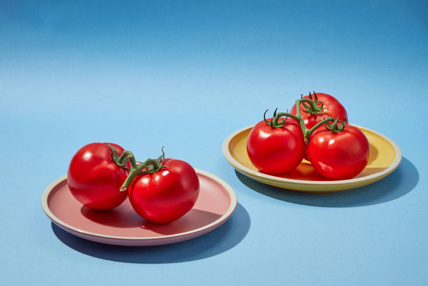 Scène voor reclame voor cosmetische producten van tomatenextract - rond geplateerd met rode verse tomaten op een blauwe achtergrond. Tomaten bevatten veel voedingsstoffen die goed zijn voor de gezondheid - Foto, afbeelding
