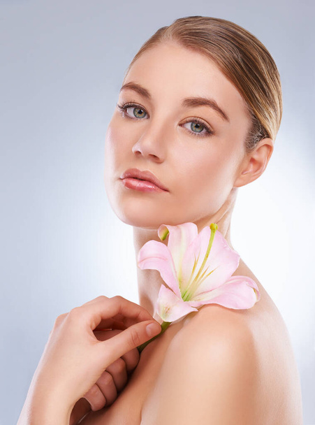 Portrait, beauty and woman with dermatology, flowers or wellness on white studio background. Face, person or model with natural cosmetics or grooming with shine or glow with aesthetic or healthy skin. - Photo, Image