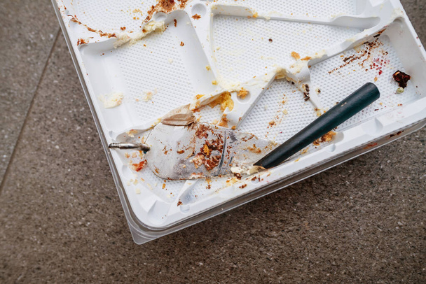 Egy felülről lefelé néző törött spatula és egy üres műanyag torta tálca morzsákkal szétszórva - Fotó, kép