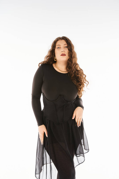 seductive curvy woman in black stylish outfit with curly hair posing with hands on hips - Φωτογραφία, εικόνα