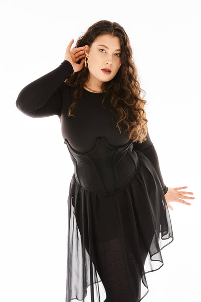 lovely curvy young woman in black stylish outfit with curly hair showing her earring - Foto, Imagem