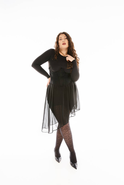 beautiful plus size woman in black stylish outfit with curly hair posing against white background - Foto, immagini