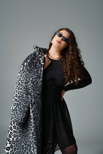 beautiful curvy woman in sunglasses posing with fur coat over shoulder and hand on waist - Photo, Image