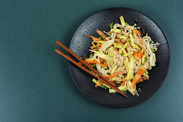 Salat aus Enoki-Pilzen und Gemüse, serviert auf einem schwarzen Teller. Asia Thai food. Kopierraum für Text. - Foto, Bild