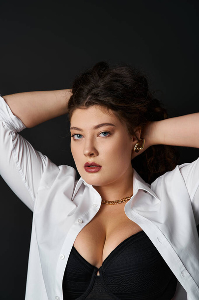 portrait of charming curvy woman in shirt and bra putting hands behind head and holding hair - Photo, Image