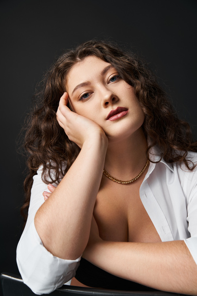 portrait of charming plus size girl in her 20s leaning on hand and looking to camera - Photo, Image