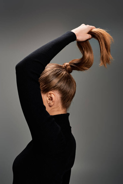 A young beautiful woman with long hair styled in a sleek and stylish ponytail. - Photo, Image