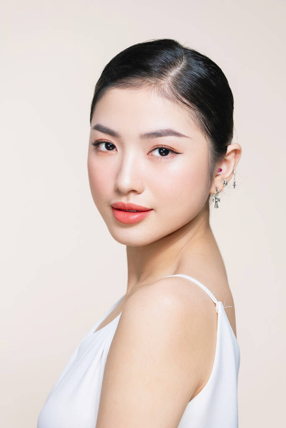 Красивая молодая азиатка с чистой свежей кожей на бежевом фоне - Фото, изображение