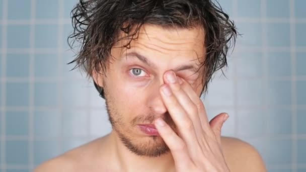 Man, hair and shower for hygiene, grooming or cleanliness in bathroom on wall background. Portrait of tired, wet or frizzy male person wakeup with clean face for washing, cleaning or skincare at home. - Footage, Video