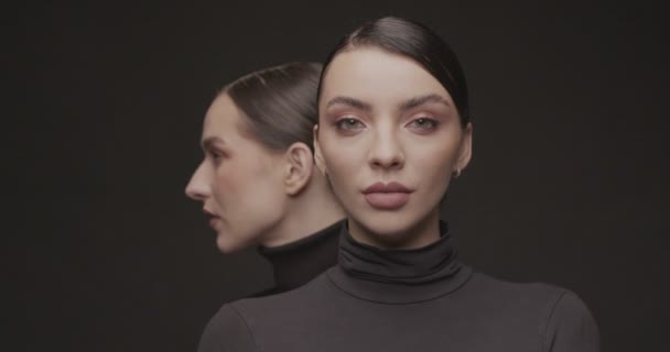 Zwei junge elegante Frauen mit gutem Make-up auf schwarzem Hintergrund. Zeitlupe, Studioaufnahme. - Filmmaterial, Video