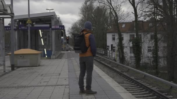 Vonattörlés Németországban. A férfi, aki a régóta késleltetett ingavonatra vár a berlini külvárosi vasútállomáson, Németországban. Zug fallt aus, Németország. A vasút késik Németországban. Városi élet polgára.  - Felvétel, videó