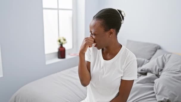 アフリカ系アメリカ人女性がベッドに横たわり,嫌悪感や耐え難い臭いに対して息を止めています. 寝室で彼女を嫌がらせする悪い匂い - 映像、動画