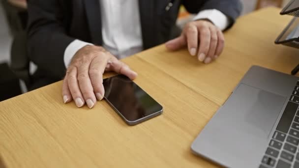 Un cadre supérieur élégant, un cadre supérieur, plongé dans le travail d'affaires au bureau, assis à son bureau, tapant sur un ordinateur portable, manipulant son téléphone portable la définition d'un professionnel à succès. - Séquence, vidéo