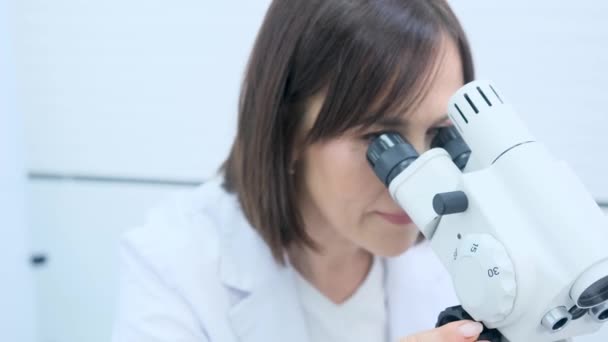 Egy nőgyógyász nő a mikroszkópba néz közelről.. - Felvétel, videó