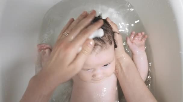 Sorgfältige Eltern waschen dunkelhaarige Kinder sanft mit Shampoo, um das Baby sauber zu halten. Sanftes Verfahren zum Waschen der Tochter vor dem Schlafengehen - Filmmaterial, Video