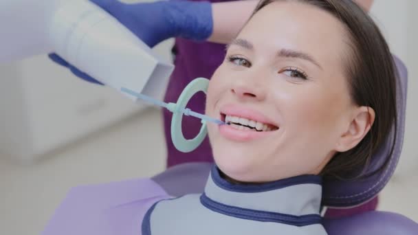 Assistente odontológico prepara paciente para raio-X usando ferramentas especializadas em clínica. Mulher pede paciente feminino para sorrir para melhor visão da boca - Filmagem, Vídeo