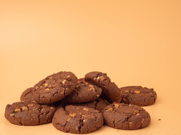 Çikolatalı, turuncu arka planda beyaz çikolata parçacıkları olan zengin kurabiyeler. Beyaz çikolatalı kurabiyeler.. - Fotoğraf, Görsel