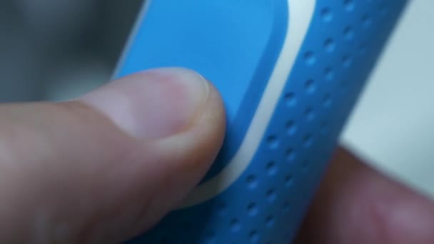 Mavi elektrikli bir diş fırçasının üzerindeki güç düğmesinin işlevselliğini ve işlevselliğini gösteren bir parmak basma ve kullanım kolaylığını gösteren yakın çekim videosu. - Video, Çekim