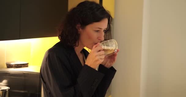 Joven mujer de negocios bebiendo café de la máquina de café en la cocina de la oficina. Mujer con traje de negocios oscuro. Imágenes de alta calidad 4k - Metraje, vídeo