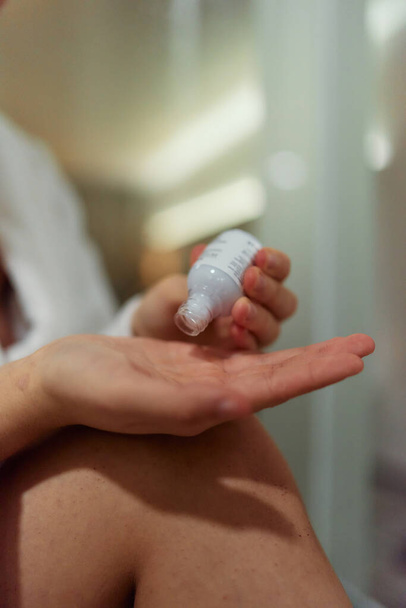 Nahaufnahme, eine Frau trägt feuchtigkeitsspendende Creme auf ihre Hand auf und frönt einem täglichen Hautpflegeritual, das Weichheit, Gesundheit und Wohlbefinden fördert. - Foto, Bild