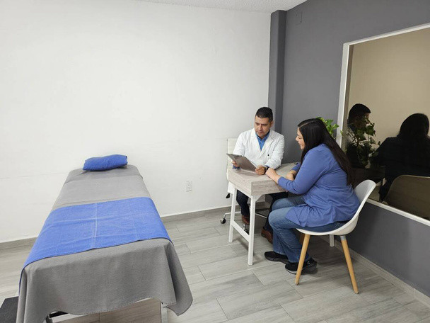 Donkerhuid mannelijke specialist arts woont vrouwelijke patiënt in overleg in zijn kantoor voor jaarlijkse medische check-up - Foto, afbeelding