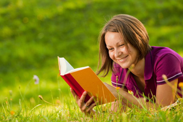 Beautiful woman laughing with a book in the park - Фото, изображение