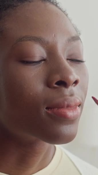 Вертикаль афроамериканской женщины с макияжем для губ, отдыхающей дома с другом - Кадры, видео