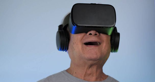 Asian old man having fun playing games while wearing virtual reality glasses. - Photo, Image