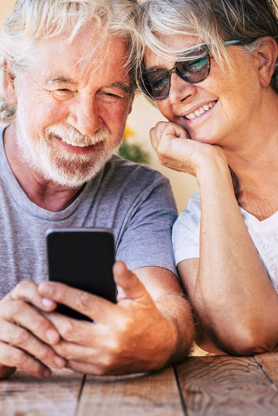 ハッピー美しい美しいシニアカップルは,現代のオンライン技術デバイスで電話をする - 愛と友情と永遠に一緒に退職した陽気な人々 - 慎重な成熟とインターネット接続 - 写真・画像