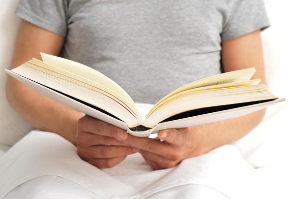 Молодой человек читает книгу в постели
 - Фото, изображение