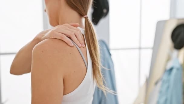 Eine junge kaukasische Frau reibt ihre schmerzhafte Schulter drinnen mit natürlichem Licht - Filmmaterial, Video