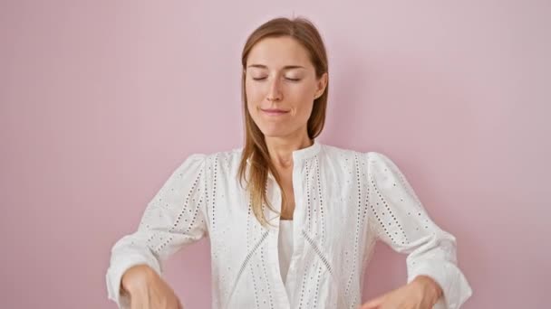 Zen meditasyonunda ışıl ışıl genç bir kadın pembe izole bir arka planda duruyor. Nefes alıyor ve gözlerini kapıyor. Huzur ve güzel, sağlıklı bir yoga yaşam tarzı yayıyor.. - Video, Çekim