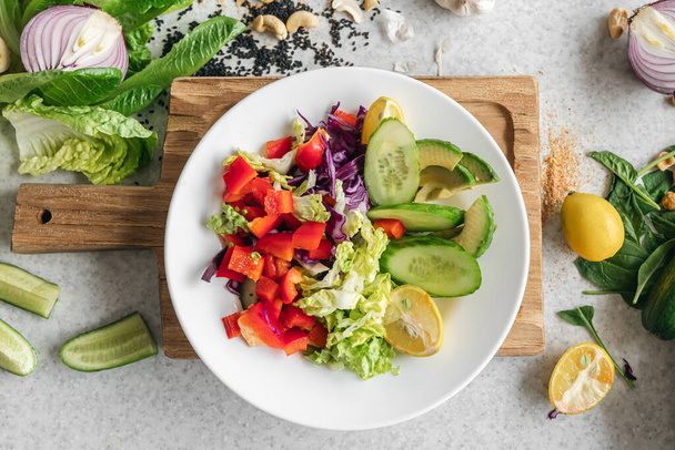 Detailní záběr, čerstvý zeleninový salát na kuchyňském stole, výhled shora. Salát z papriky, zelí a okurky. Syrový zeleninový salát, vegetariánský. - Fotografie, Obrázek