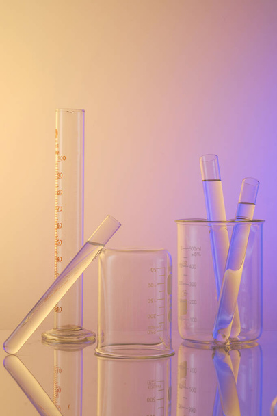 Verticaal frame met laboratoriumapparatuur - bekerglas en reageerbuizen met transparante oplossing. Wetenschappelijk laboratoriumconcept voor onderzoek en ontwikkeling. Lege ruimte voor reclame. - Foto, afbeelding
