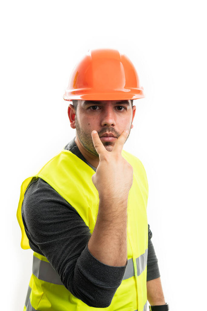 Модель как конструктор мужчина в оранжевом шлеме безопасности и флуоресцентной одежде делает жест зрительного контакта указывая пальцами в качестве надзирателя концепции изолированы на белом - Фото, изображение