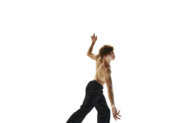 現代バレエ。 腕のあるシャツレスの男性ダンサーが立ち上がり,白いスタジオの背景に対して上昇した. 芸術の概念,人間の動き,健康,男性のボディの自然な美. - 写真・画像
