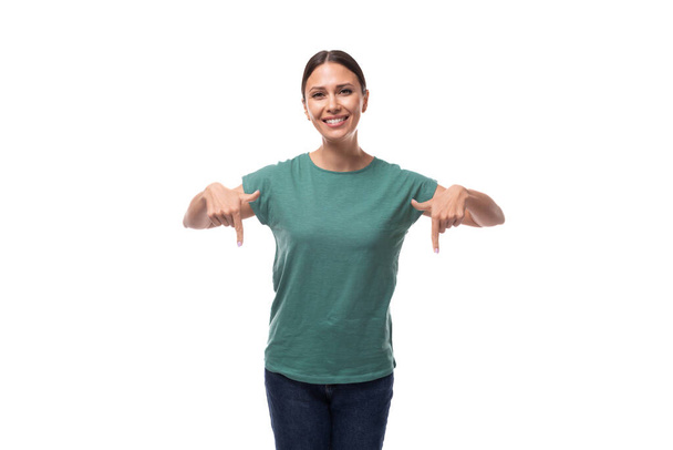 joven mujer de pelo negro vestida con una camiseta básica muestra su mano hacia abajo con sorpresa. - Foto, Imagen