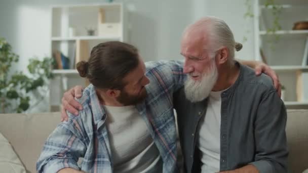 Familiegesprek op de bank: jonge en oudere mannen praten over het leven, psychologische ondersteuning voor elkaar, intergenerationele dialoog, oprechte troost, advies en wijsheid, warme communicatie - Video