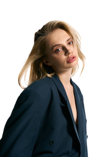 appealing woman with blonde hair in stylish blazer posing on white backdrop and looking at camera - Photo, image