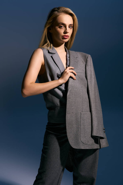 elegant woman in silver chic vest and suit posing on dark blue backdrop and looking at camera - Fotografie, Obrázek