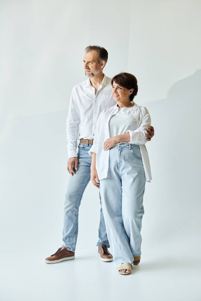 Full length image of mature beautiful couple standing on grey background, looking away - Foto, imagen
