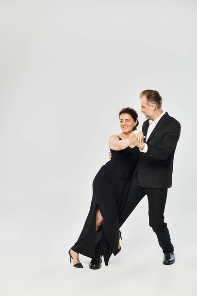 Full length shot of mature attractive couple in a tango dance pose isolated on grey background - Photo, Image